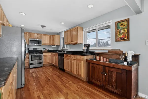 a kitchen with stainless steel appliances granite countertop wooden cabinets a stove a sink and dishwasher with wooden floor