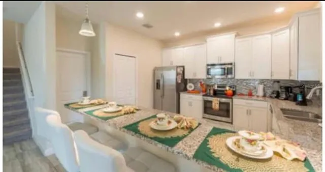 a kitchen with stainless steel appliances kitchen island granite countertop a dining table and chairs