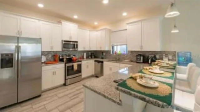 a kitchen with stainless steel appliances granite countertop a sink and a refrigerator