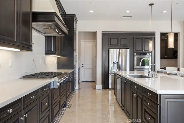 a large kitchen with a large counter top a sink stainless steel appliances and cabinets