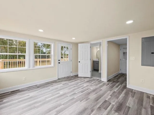 a view of an empty room with wooden floor and a window