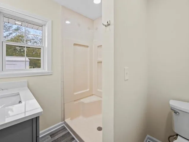 a bathroom with a granite countertop sink a toilet and a shower