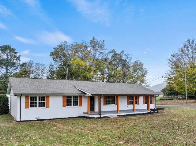 a view of a white house with a yard and large trees