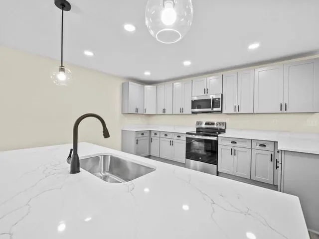 a kitchen with stainless steel appliances kitchen island granite countertop a sink a stove and a wooden floors