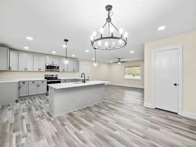 a large kitchen with kitchen island white cabinets and chandelier
