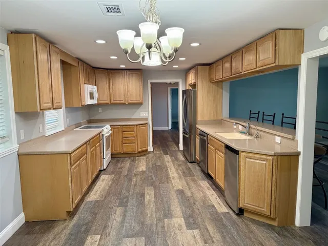 a large kitchen with stainless steel appliances wooden floors and large cabinets