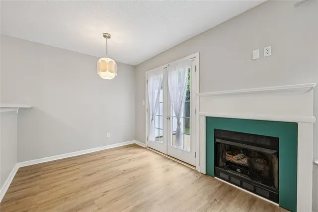 an empty room with wooden floor fireplace and window