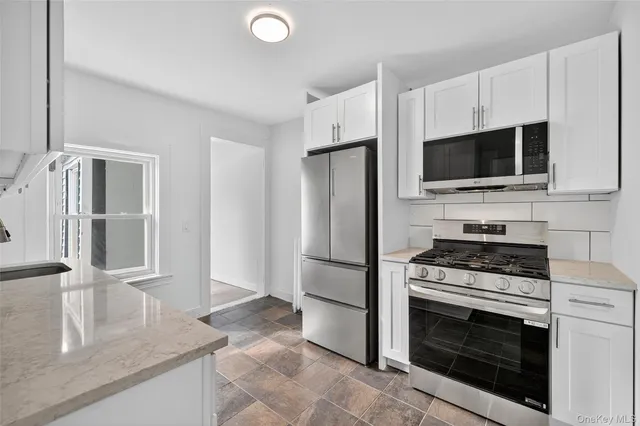 a kitchen with granite countertop a stove microwave and refrigerator