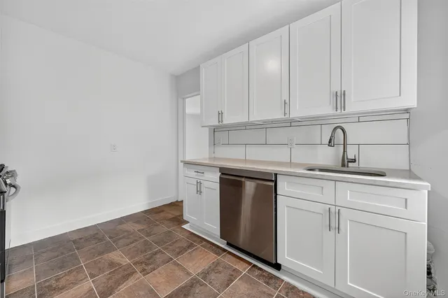 a kitchen with white cabinets and sink