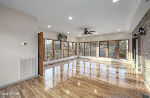a view of an empty room with wooden floor and a window