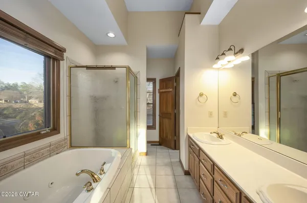 a spacious bathroom with a tub sink shower and a mirror
