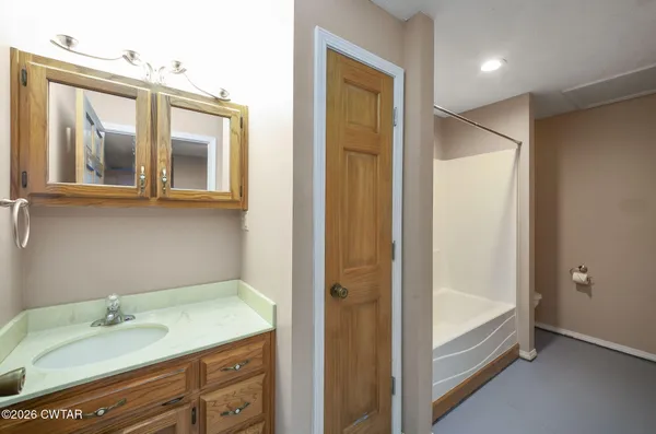 a en suite bathroom with a granite countertop sink mirror and bathtub