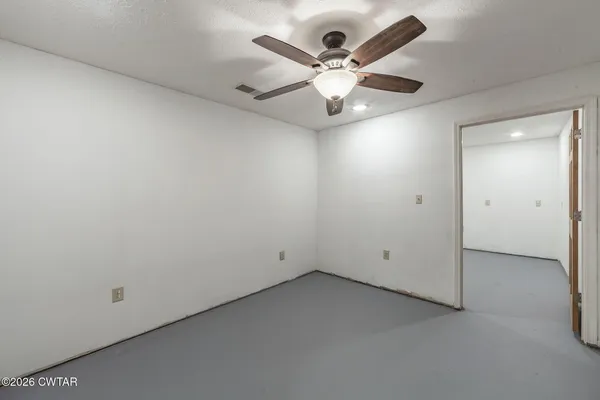 an empty room with a window and a fan