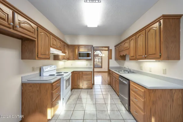 a large kitchen with stainless steel appliances granite countertop wooden cabinets a sink and dishwasher