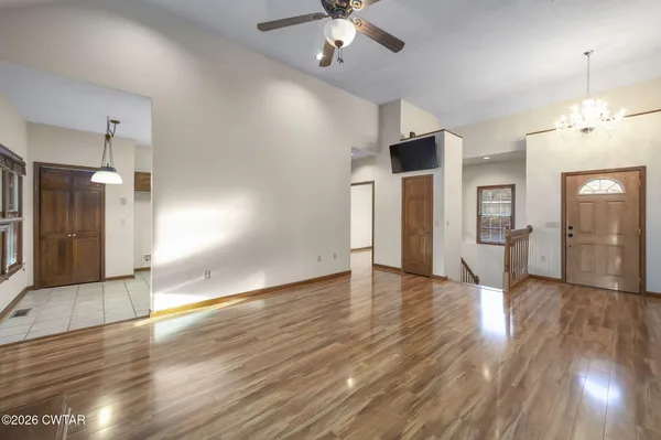 a view of an empty room with wooden floor and a kitchen