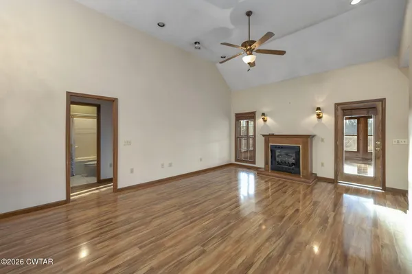 an empty room with wooden floor fireplace and windows