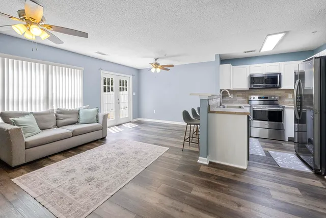a living room with stainless steel appliances furniture and a window