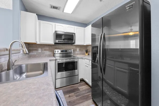 a kitchen with stainless steel appliances a refrigerator sink and microwave