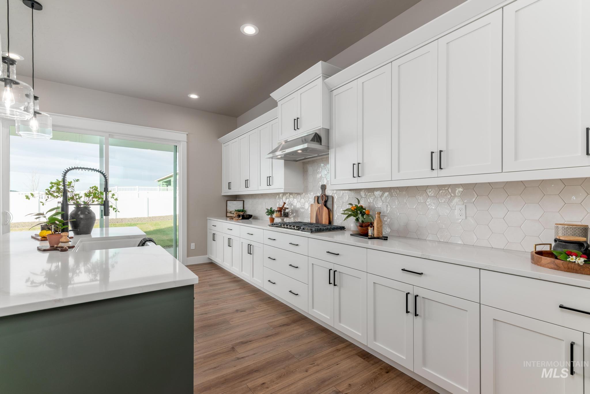 15249 Steel Cloud Avenue Caldwell, ID 83607 - Photo 12 of 46 Kitchen with pendant lighting, white cabinetry, light stone counters, light wood-style floors, and under cabinet range hood