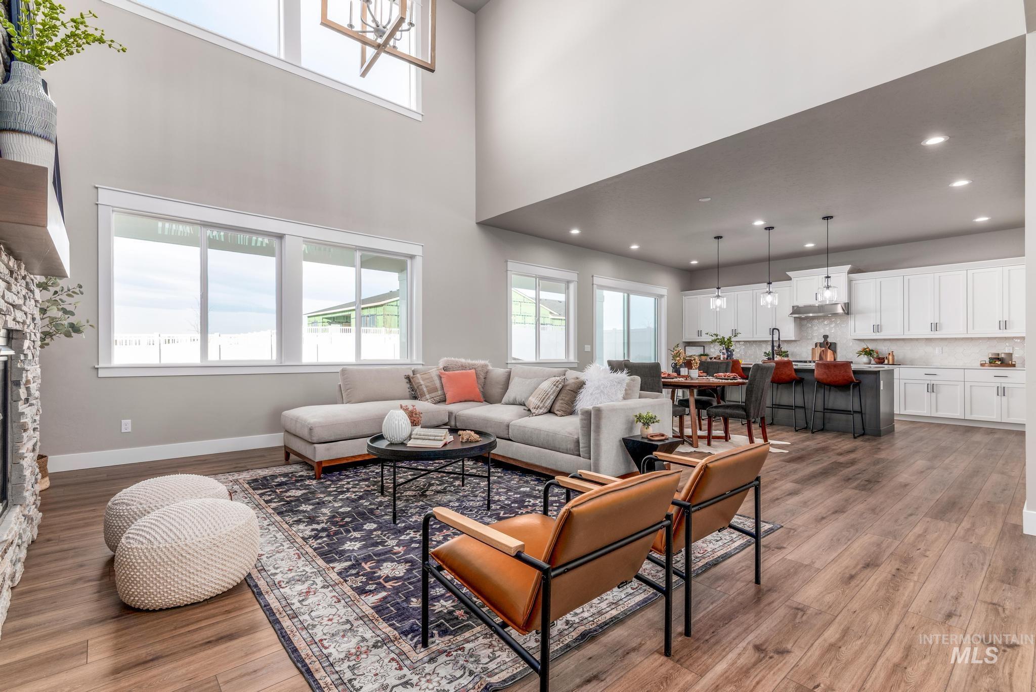 15249 Steel Cloud Avenue Caldwell, ID 83607 - Photo 9 of 46 Living room with light wood-style floors, a high ceiling, a stone fireplace, and recessed lighting