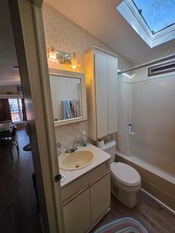a bathroom with a granite countertop sink toilet a mirror and shower