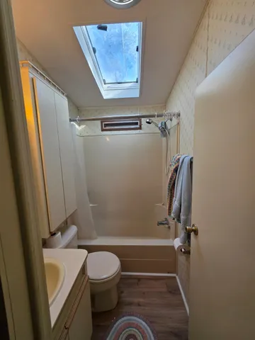 a bathroom with a granite countertop bathtub shower sink vanity and toilet