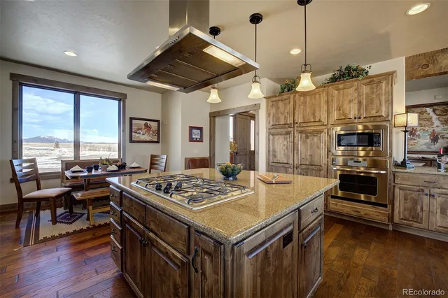 a view of a dining hall with stainless steel appliances granite countertop a stove refrigerator and cabinets