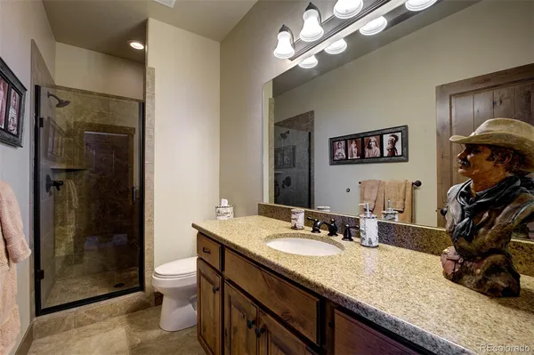 a bathroom with a granite countertop sink a mirror a toilet and shower