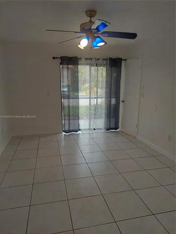 a view of an empty room with a chandelier fan