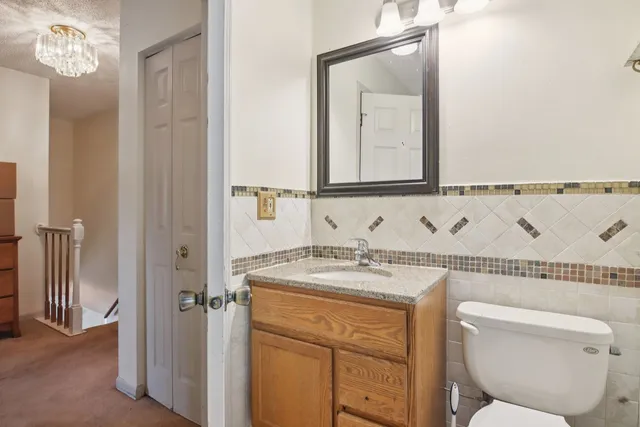 a bathroom with a granite countertop sink a toilet mirror and vanity