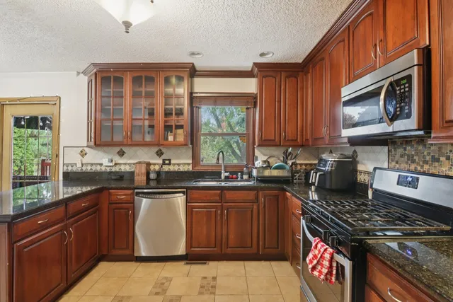 a kitchen with stainless steel appliances granite countertop wooden cabinets stove top oven and sink