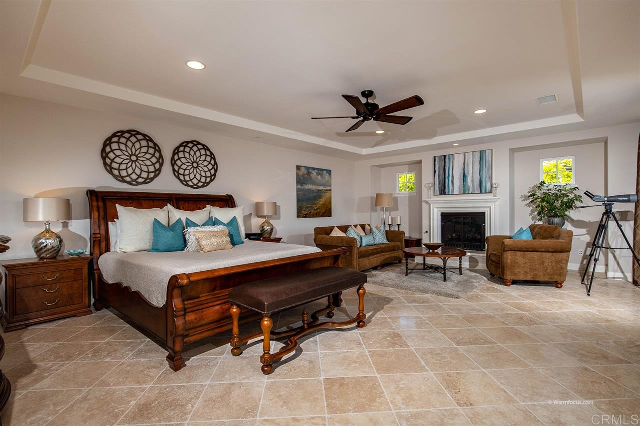 Huge master suite with fireplace retreat, tray ceiling and tumbled travertine floors laid on a diagonal.