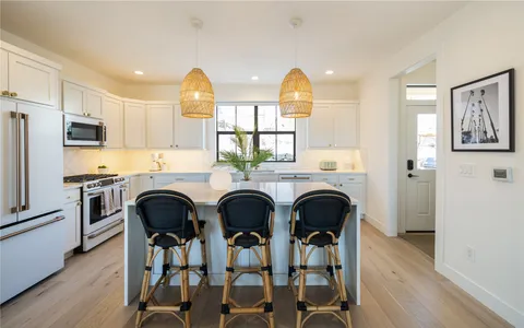 a kitchen with stainless steel appliances a dining table chairs refrigerator and sink