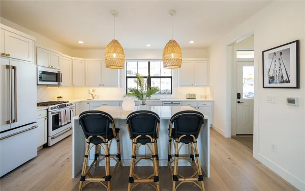 a kitchen with stainless steel appliances a dining table chairs refrigerator and sink