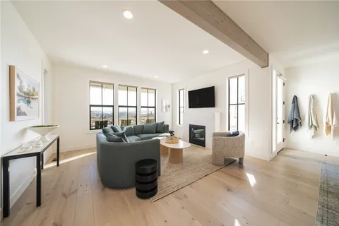 a living room with furniture a large window and a wooden floor