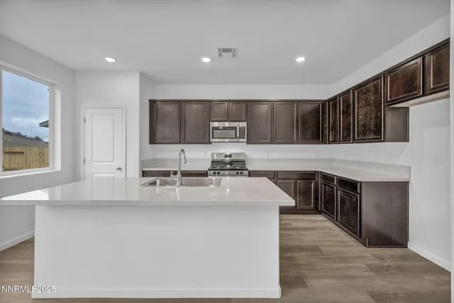 a kitchen with stainless steel appliances granite countertop a stove a sink and a microwave