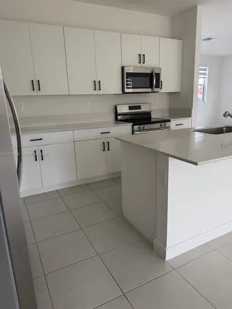 a kitchen with stainless steel appliances a sink a stove a microwave a sink and cabinets