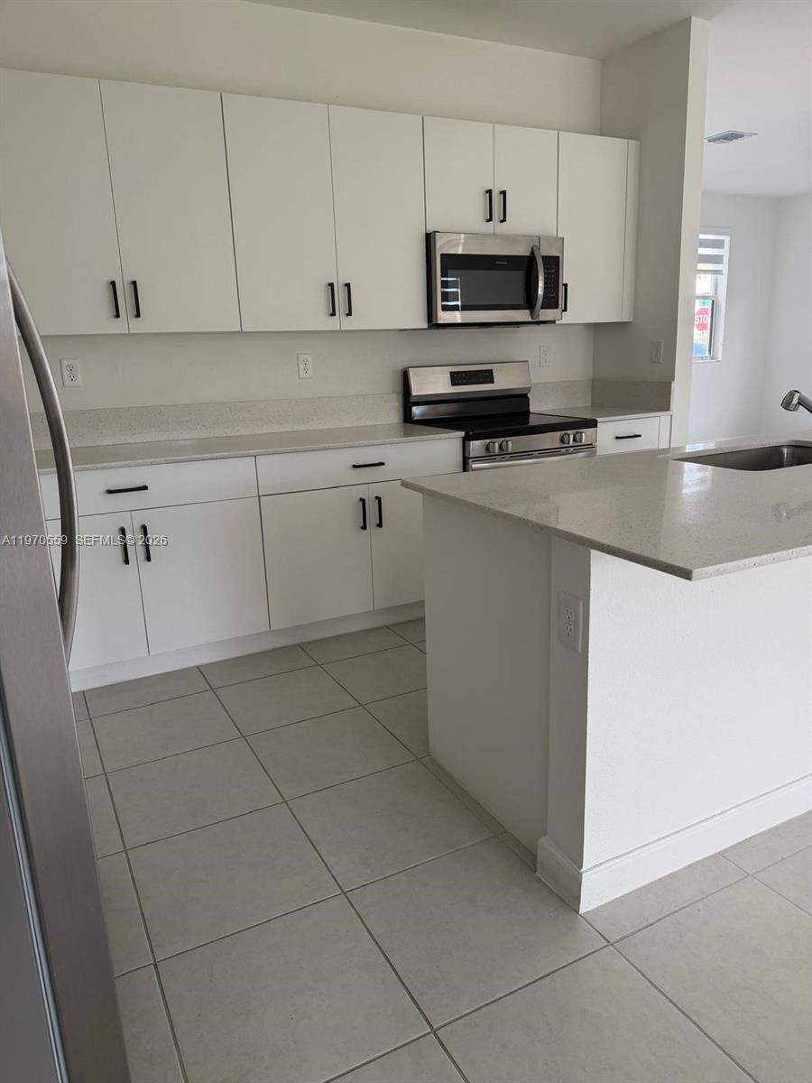 2638 Southeast 9th Street Homestead, FL 33035 - Photo 10 of 36 a kitchen with stainless steel appliances a sink a stove a microwave a sink and cabinets