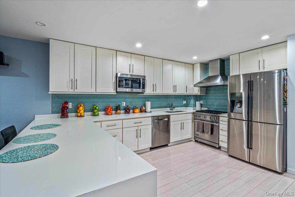 208-06 Robert Road, Unit 2 Queens, NY 11360 - Photo 8 of 26 a kitchen with kitchen island granite countertop a refrigerator oven a sink dishwasher and white cabinets with wooden floor