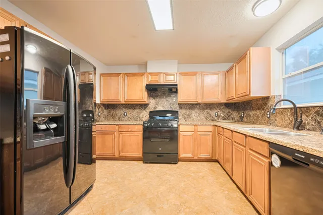 a kitchen with granite countertop a stove top oven sink and cabinets