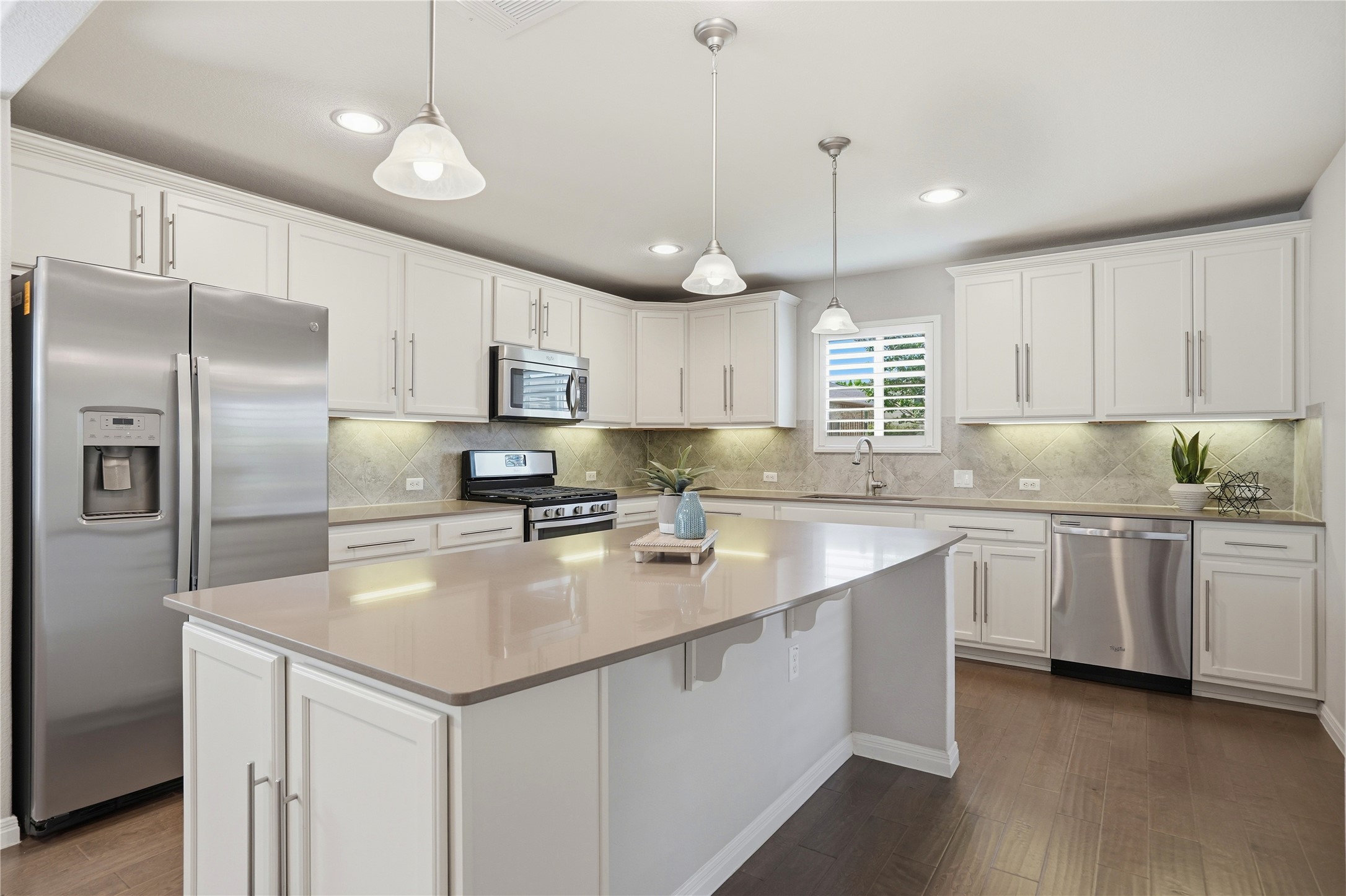 821 Hamilton Lane Georgetown, TX 78633 - Photo 6 of 38 Kitchen features white cabinetry, stainless steel appliances, a large center island with quartz countertops, recessed lighting, and wood floors