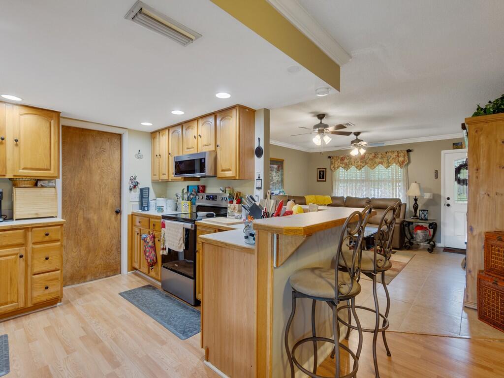 3118 Old Edwards Road Fort Pierce, FL 34981 - Photo 4 of 35 a kitchen with stainless steel appliances kitchen island granite countertop a refrigerator a stove top oven a sink dishwasher and white cabinets with wooden floor