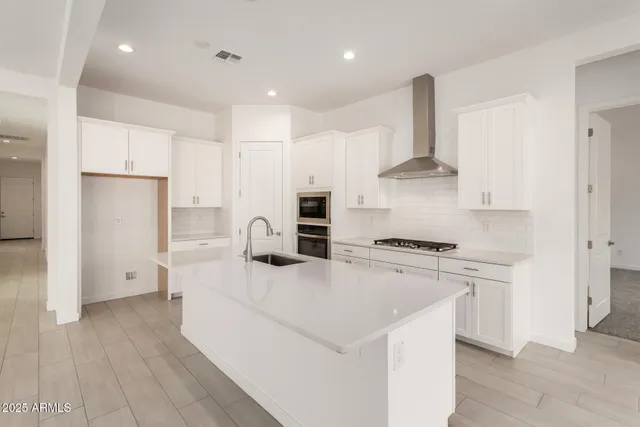 a kitchen with stainless steel appliances a refrigerator a stove and white cabinets
