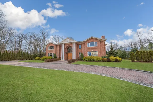 a front view of a house with a yard and large trees