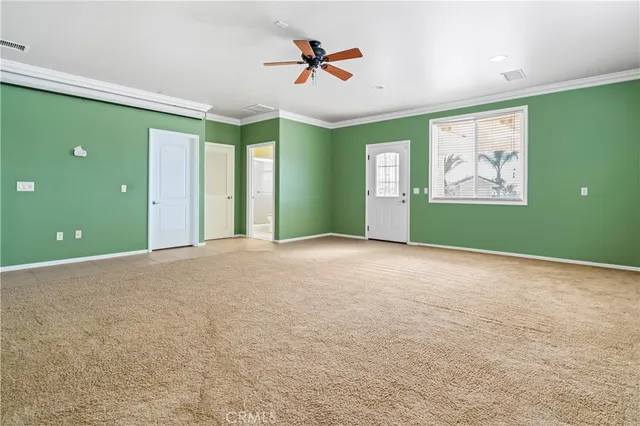 a view of an empty room with window and ceiling fan