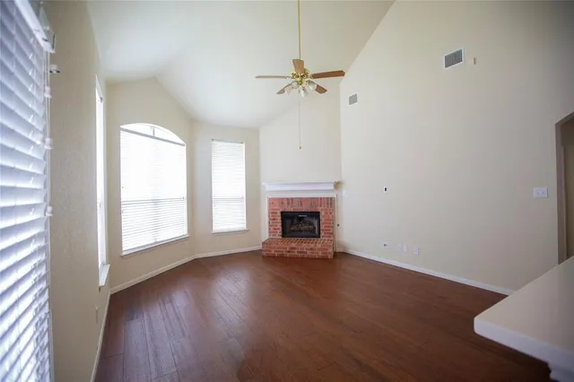 an empty room with wooden floor fireplace and windows