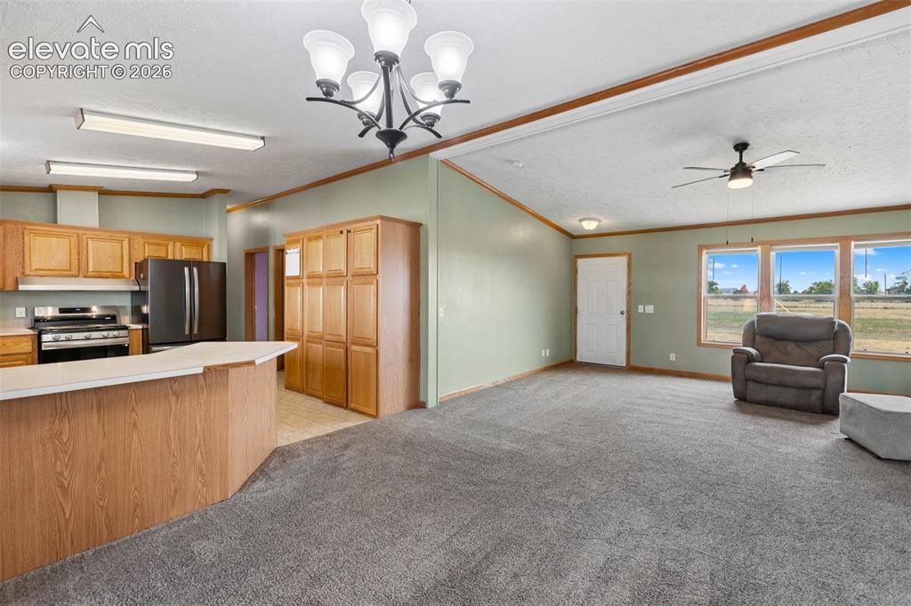 1350 South Calhan Highway Yoder, CO 80864 - Photo 19 of 45 Open-concept living space featuring a kitchen with light wood cabinetry, a breakfast bar, and a full suite of black appliances