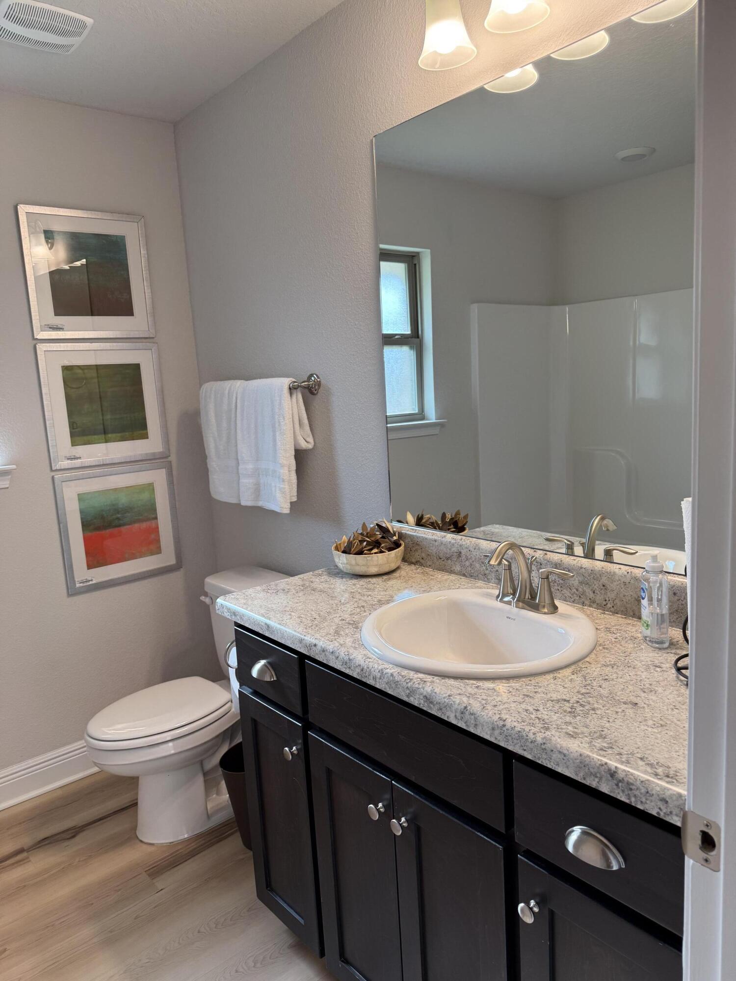 5825 Crestlake Drive Crestview, FL 32536 - Photo 10 of 29 a bathroom with a granite countertop toilet a sink and a mirror
