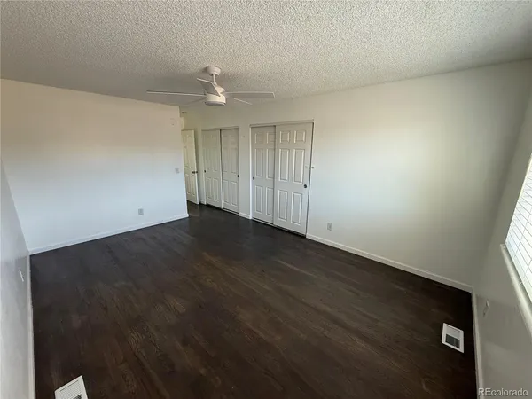 an empty room with wooden floor and fan