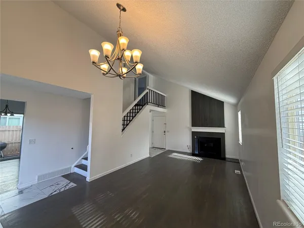a view of a livingroom with a fireplace a chandelier and windows